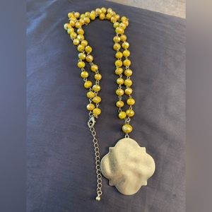 Yellow bead necklace with gold tone metal charm